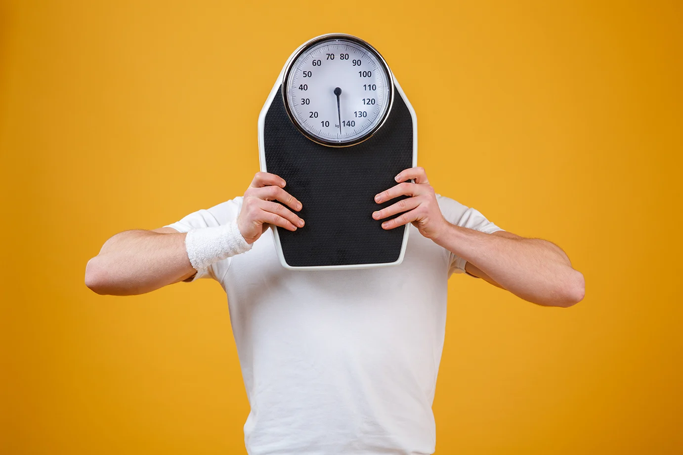 young-sports-man-hiding-face-weight-scales